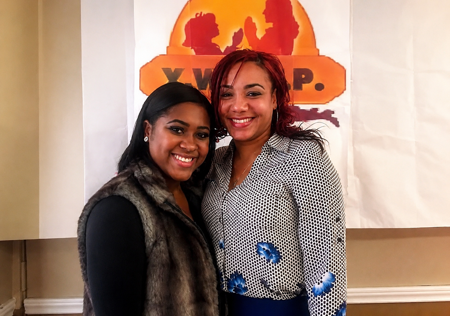 Two Y.W.H.I.P. members smiling in front of the Y.W.H.I.P. banner